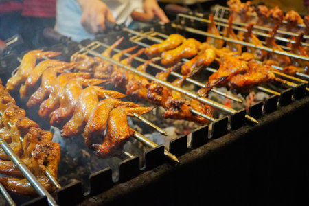 Grilling chicken wings with charcoal that is turned manually by hand.の写真素材