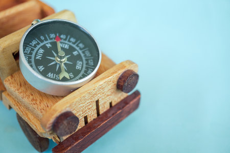 Wooden toy car carrying a compass isolated on sky blue background.の写真素材