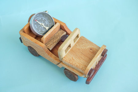 Wooden toy car carrying a compass isolated on sky blue background.の写真素材