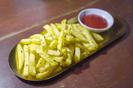 French fries and chili sauce on a wooden table background.