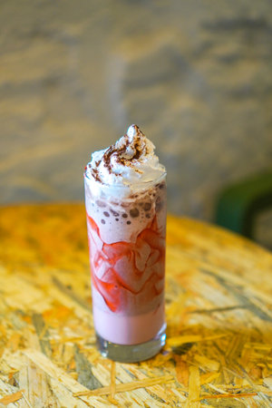 Strawberry flavored milk cafe drink topped with cream and chocolate sprinkles.