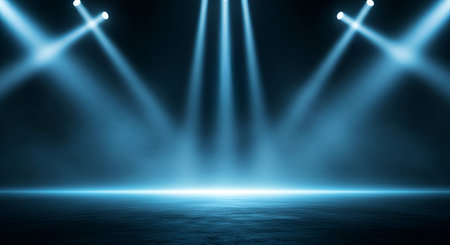 A dark stage floor is illuminated by a central cluster of blue spotlights and two additional spotlights positioned on the sides, casting angled beams. A bright horizontal line of light runs across the floor. The atmosphere is hazy and illuminated, creating a dramatic effect suitable for a performance.の写真素材