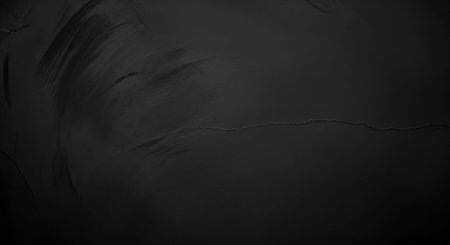 A dark, textured surface with subtle, organic swirls and a fine crack running across it. The color is a deep charcoal grey, with a matte finish that absorbs light. The texture suggests a rough material like concrete or stone, creating a minimalist and slightly distressed aesthetic.の写真素材