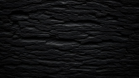A detailed, close-up view of a dark, textured surface. The pattern is rough and uneven, with deep crevices and ridges, resembling the bark of a tree or a coarse stone. The lighting creates strong shadows, enhancing the ruggedness of the material.の写真素材