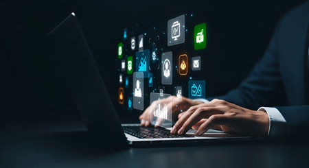 Close-up of a person's hands typing on a laptop keyboard. Above the laptop, a stream of colorful, glowing digital icons representing various applications and data visualizations floats in the air, creating a futuristic and dynamic digital environment.の写真素材