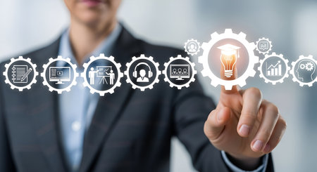 A businessman in a suit and tie is shown with his finger pointing towards a series of interconnected gear icons. These icons represent various aspects of education and technology, including a document, a computer screen with a video player, a person giving a presentation, headphones, another computer screen, a graduation cap illuminating a lightbulb, a bar chart, and a brain icon. The image symbolizes the integration of technology in learning and professional development.の写真素材