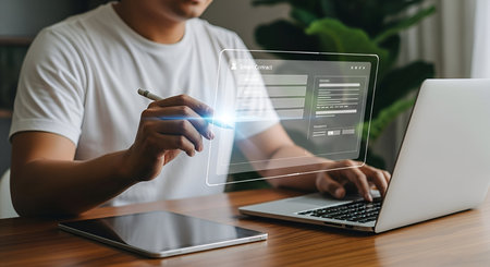 A person is shown interacting with a holographic digital screen displaying a "Smart Contract" form. Their hand holds a stylus, pointing at the screen, while their other hand rests on a laptop keyboard. A tablet is also on the wooden desk. The image conveys digital contract signing and online agreements.の写真素材