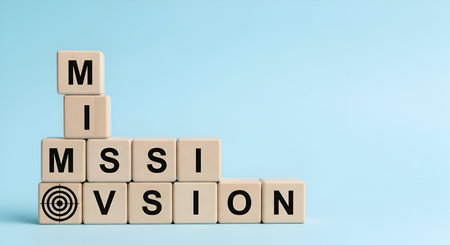 Wooden blocks are arranged in a stepped pattern, spelling out the words "MISSION" and "VISION". The first block of "MISSION" features a target with a bullseye, symbolizing a clear objective. The arrangement suggests a progression towards achieving goals and aligning with a company's purpose.の写真素材