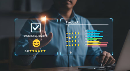 A person is shown touching a digital screen displaying customer satisfaction feedback. The interface includes a checkmark icon, a smiley face, a5-star rating, and a bar graph representing feedback data. The background is dark, with the interface illuminated by blue and yellow light.の写真素材