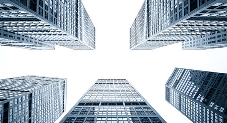 A striking low-angle shot captures the geometric patterns of modern skyscrapers reaching towards a bright, overcast sky. The repeating windows and sharp lines of the buildings create a sense of scale and urban density. The composition draws the eye upward, emphasizing the height and architectural design of the structures.の写真素材