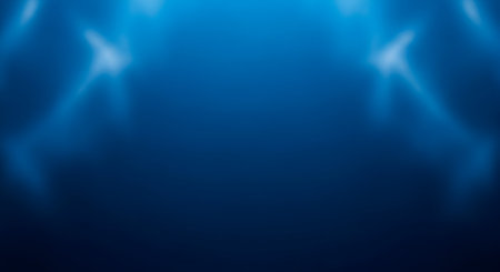 An abstract background in varying shades of deep blue. Soft, diffused light sources create luminous, ethereal effects, appearing as gentle glows or blurred spotlights on either side of the upper portion of the image. The overall impression is smooth, clean, and atmospheric, with a subtle gradient of color.の写真素材