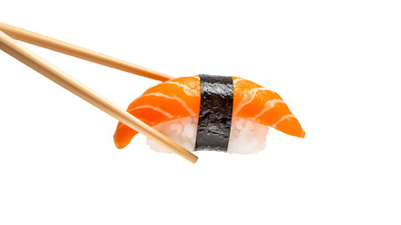 A piece of salmon nigiri sushi is held by a pair of wooden chopsticks against a solid black background. The sushi consists of a slice of vibrant orange salmon draped over a bed of white rice, secured with a strip of dark seaweed. The chopsticks are positioned to grip the sushi from the sides.の写真素材