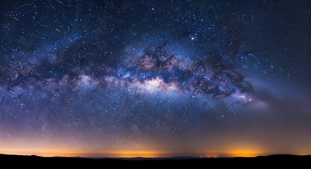 A breathtaking panoramic view of the Milky Way galaxy stretches across the night sky, filled with...