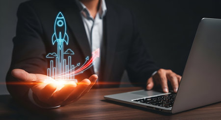 A man in a suit holds a glowing holographic rocket launching from a platform in his palm. The rocket...