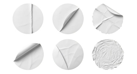 A collection of six circular white stickers presented against a black background. Each sticker displays varying degrees of wear and tear, including torn edges, peeling corners, and crumpled textures. Some stickers are fully intact, while others show signs of being lifted or removed.の写真素材