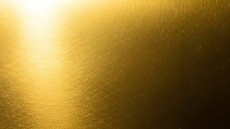 A close-up view of a brushed gold metal surface. The texture features fine, parallel lines creating...
