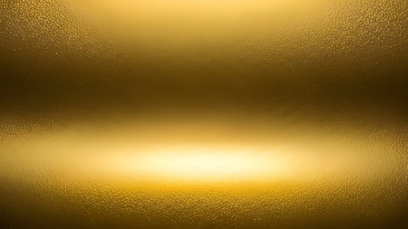 A close-up, abstract view of a textured golden surface. A bright, diffused light source illuminates the lower center of the image, creating a strong highlight and casting soft shadows that define the undulating texture. The texture appears to be a fine, granular pattern across the entire surface, with a smooth gradient from bright gold to a deeper, richer tone towards the top.の写真素材