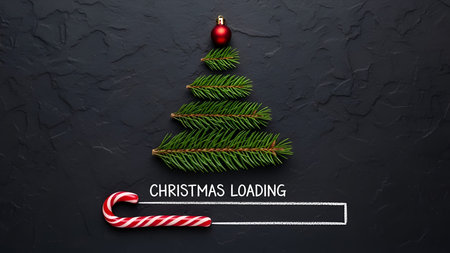 The a minimalist Christmas-themed loading screen. A small pine tree made of individual pine needles is centered on a dark, textured background. At the of the pine tree, there is a single red Christmas ornament. Below the tree, a candy cane serves as the progress bar for the loading indicator, with the text "CHRISTMAS LOADING" displayed beneath it. The overall is simple and festive, holiday-themed digitalの写真素材