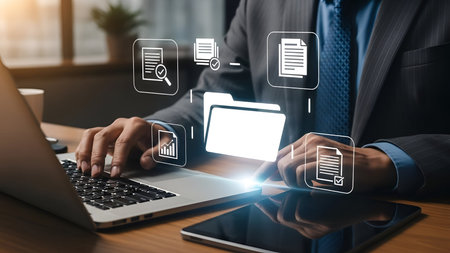 A businessperson in a suit and tie is using a laptop on a wooden desk in an office setting. Above...