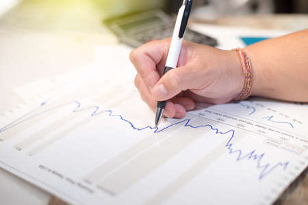 Business holding pen and think with chart and calculatorの写真素材