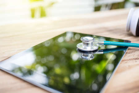 Doctor workplace with digital tablet and stethoscope on bokeh backgroundの写真素材