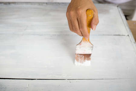 Hand with brush paint white wooden tableの写真素材