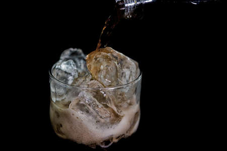 Pouring coal in a glass with ice on a black backgroundの写真素材