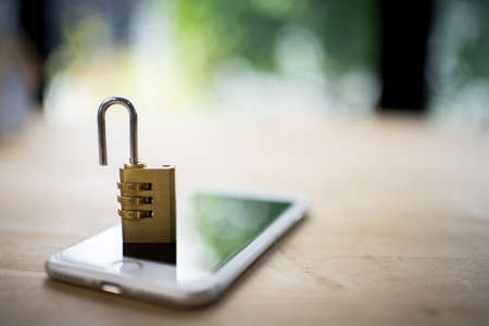 Padlock on blur phone over colorful lighting,phone data security concept.の写真素材
