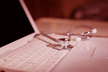 Computer or data analysis - Stethoscope over notebook keyboard toned in redの写真素材