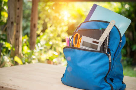 Backpack with school supplies on wooden tableの写真素材