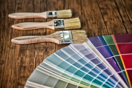 Painter and decorator work table with house project, color swatches, painting roller and paint brushes High Dynamic Range toneの写真素材