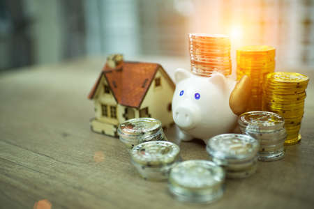 piggy bank for saving with pile of coins on table at home.A pink piggy bank are smile and happy while standing over pile of coins.の写真素材