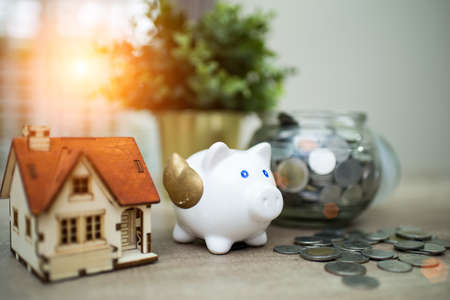 piggy bank for saving with pile of coins on table at home.A pink piggy bank are smile and happy while standing over pile of coins.の写真素材