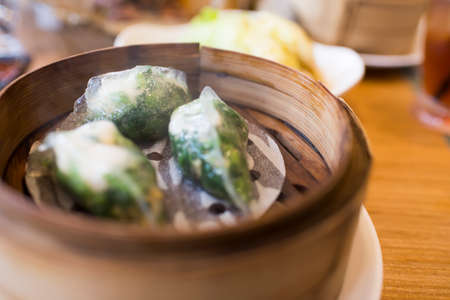 Chinese dim sum in bamboo steamer box on tableの写真素材