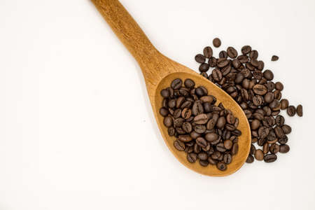 Coffee beans in wooden spoon isolated on white backgroundの写真素材