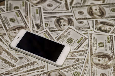 Shopping online in phone on One hundred dollars pile as background  High Dynamic Range toneのeditorial素材