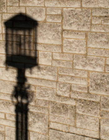 Shadow of vintage style street lamp on stone wall