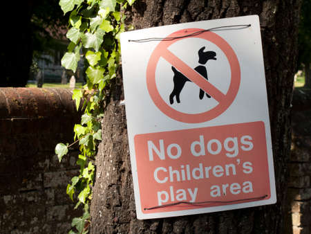 No dogs childrens play area warning sign mounted on tree trunkの写真素材