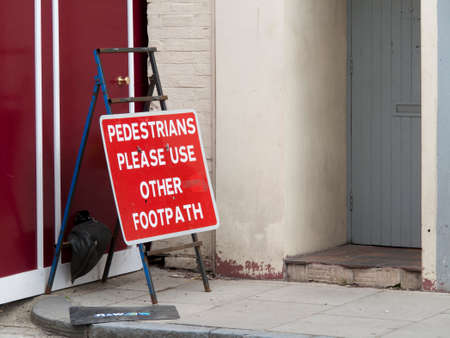 Pedestrians use other footpath sign due to construction site hoarding blocking pavementのeditorial素材