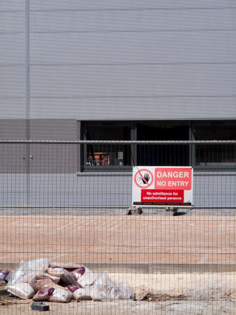 Danger no entry sign mounted on security fencing, new commercial warehouse and office developmentのeditorial素材