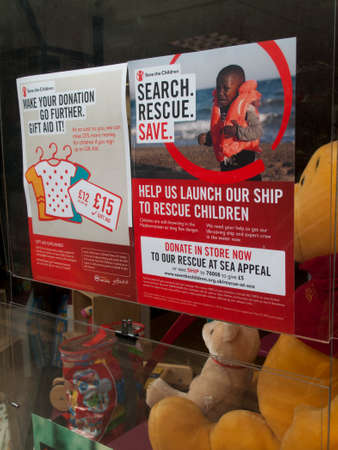 Save the Children poster in charity shop window, rescue refugee boat children appeal
