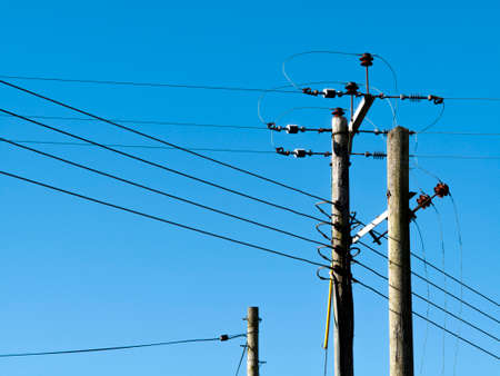 overhead electrical power transmission and distribution cables against a clear blue sky