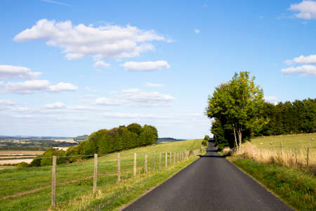 Single lane country road through countryside and farmland