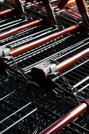 shopping trollies stored outside Sainsburys supermarket entrance with coin operated security devicesのeditorial素材
