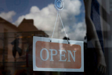 Open for business sign on shop door glass to retail premises