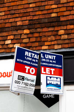 Broken retail unit to let estate agent advertising sign over vacant shop premisesのeditorial素材