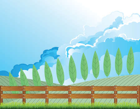 Picturesque rural country scene with farmland and boundary fence with cloudy blue sky aboveの写真素材