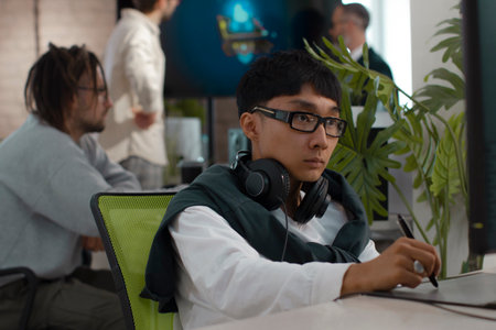 Asian male artist of 3D models works in studio for development of computer games