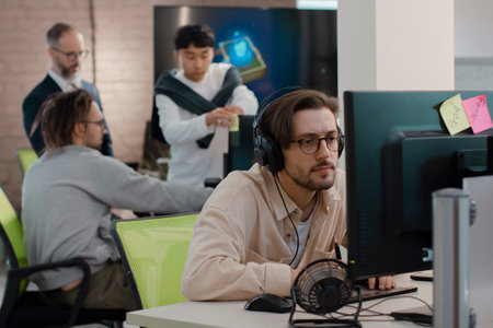 Caucasian designer in headphones draws on tablet 3D models for games.