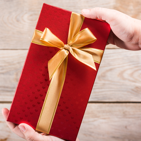 Gift box with ribbon in handsの写真素材